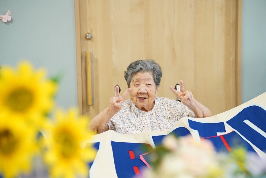 お祝いされて笑顔でピースする利用者さま