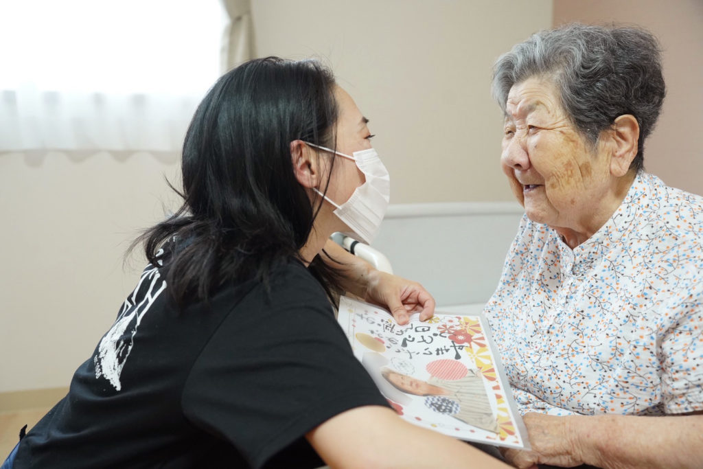 メッセージカードを手に笑顔で話す利用者さまとスタッフ