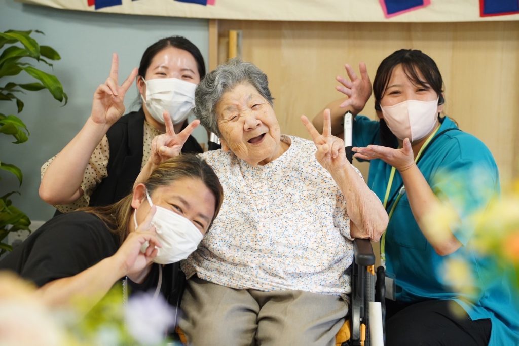 利用者さまを囲んで笑顔でお祝いするスタッフたち
