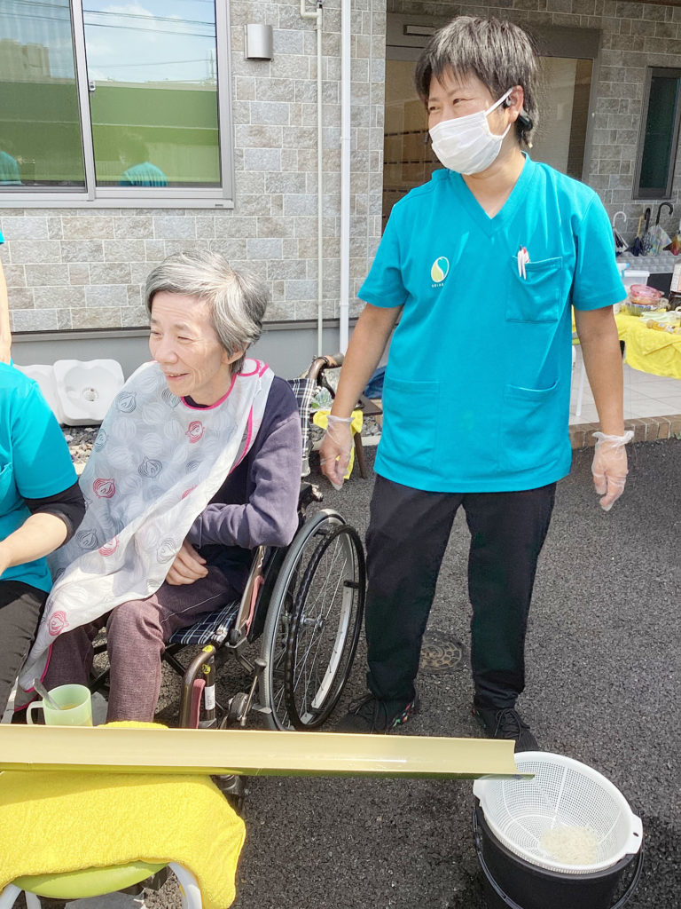 笑顔で流しそうめんを待つ利用者さまとスタッフ