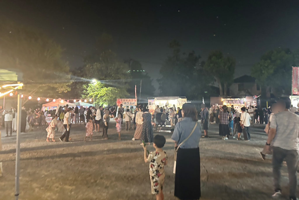 屋台が並びたくさんの参加者がいる夜のお祭り