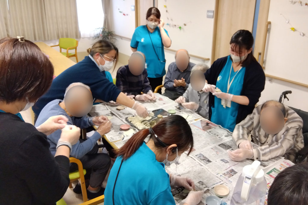 スタッフと入居者さまたちが餃子を包んでいる様子