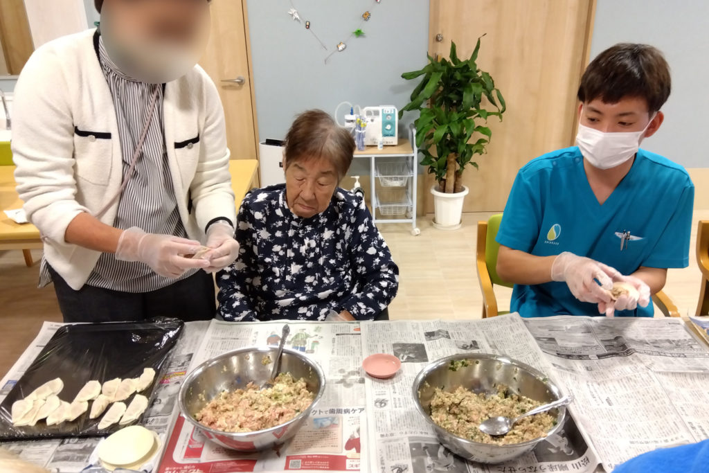 餃子を包むスタッフたちと入居者さま