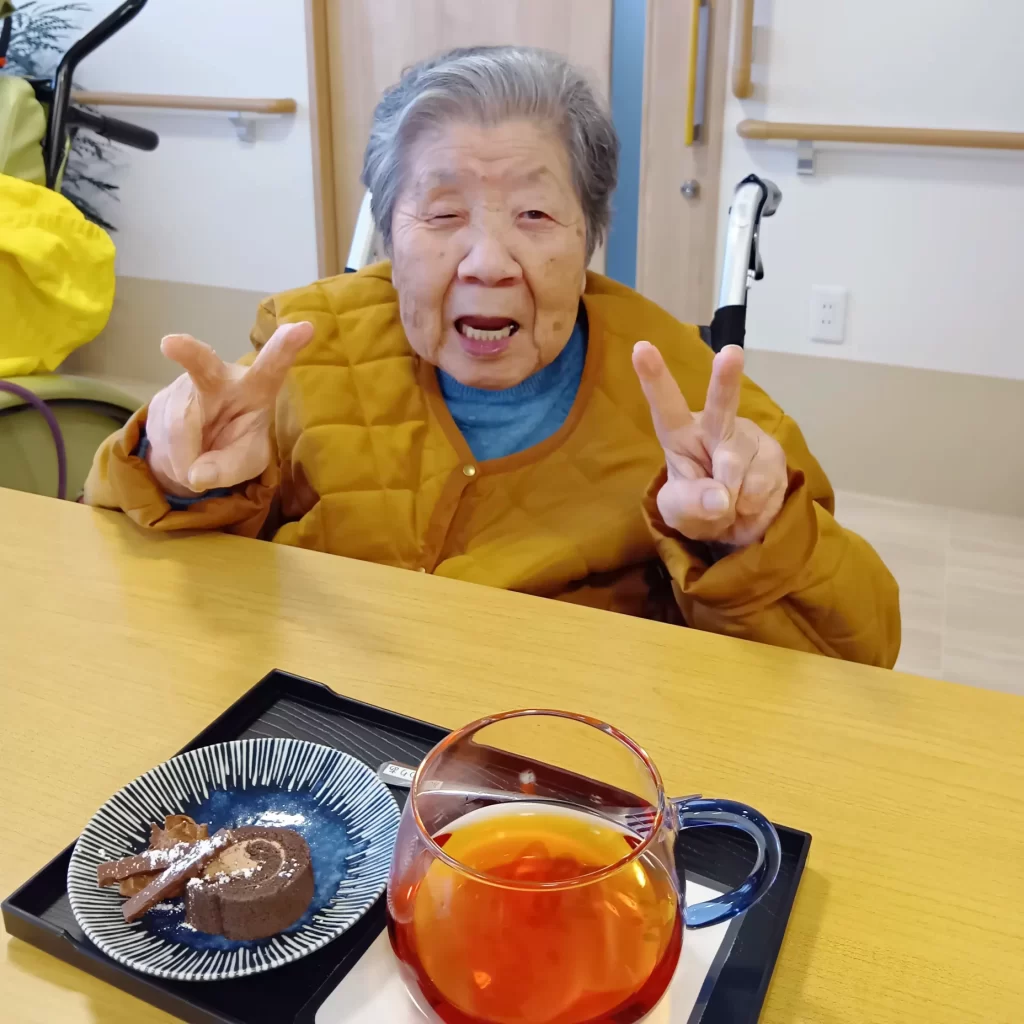 ハーブティーとデザートのセットを前にダブルでピースしている入居者さま