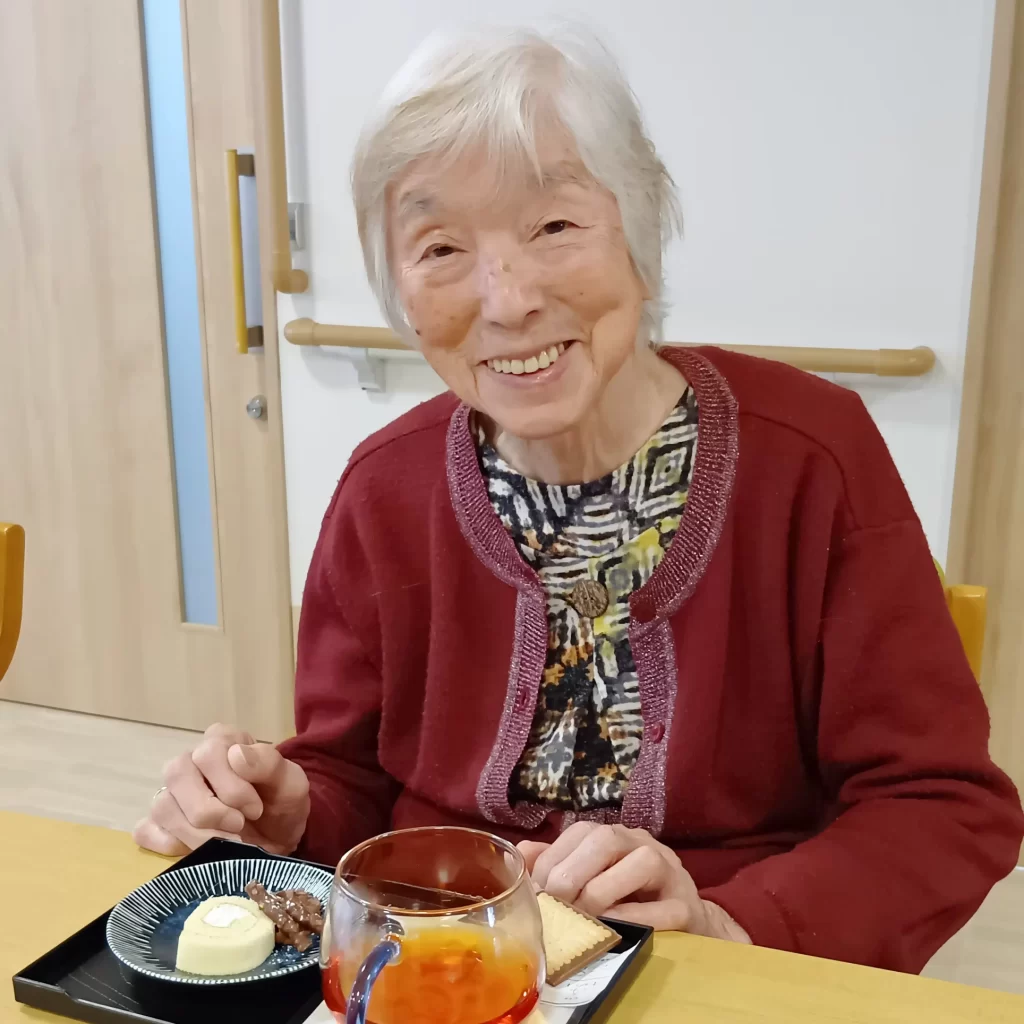 ハーブティーとデザートのセットを前に笑顔の入居者さま