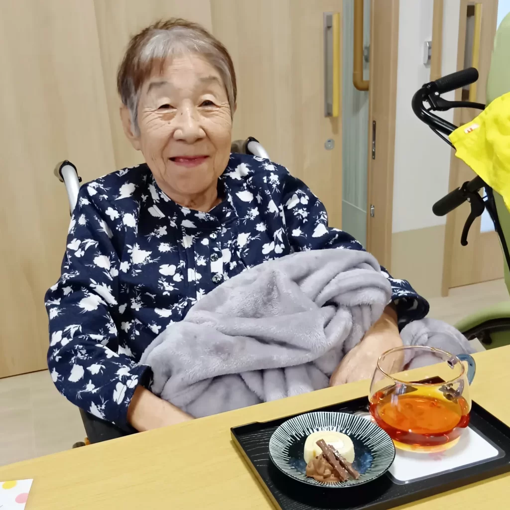 ハーブティーとデザートのセットを前に笑顔の入居者さま