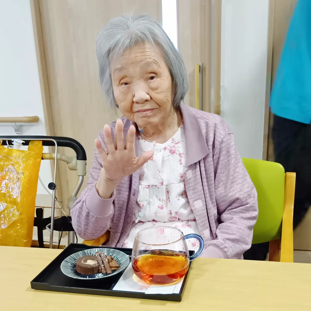 ハーブティーとデザートのセットに手をかざす入居者さま